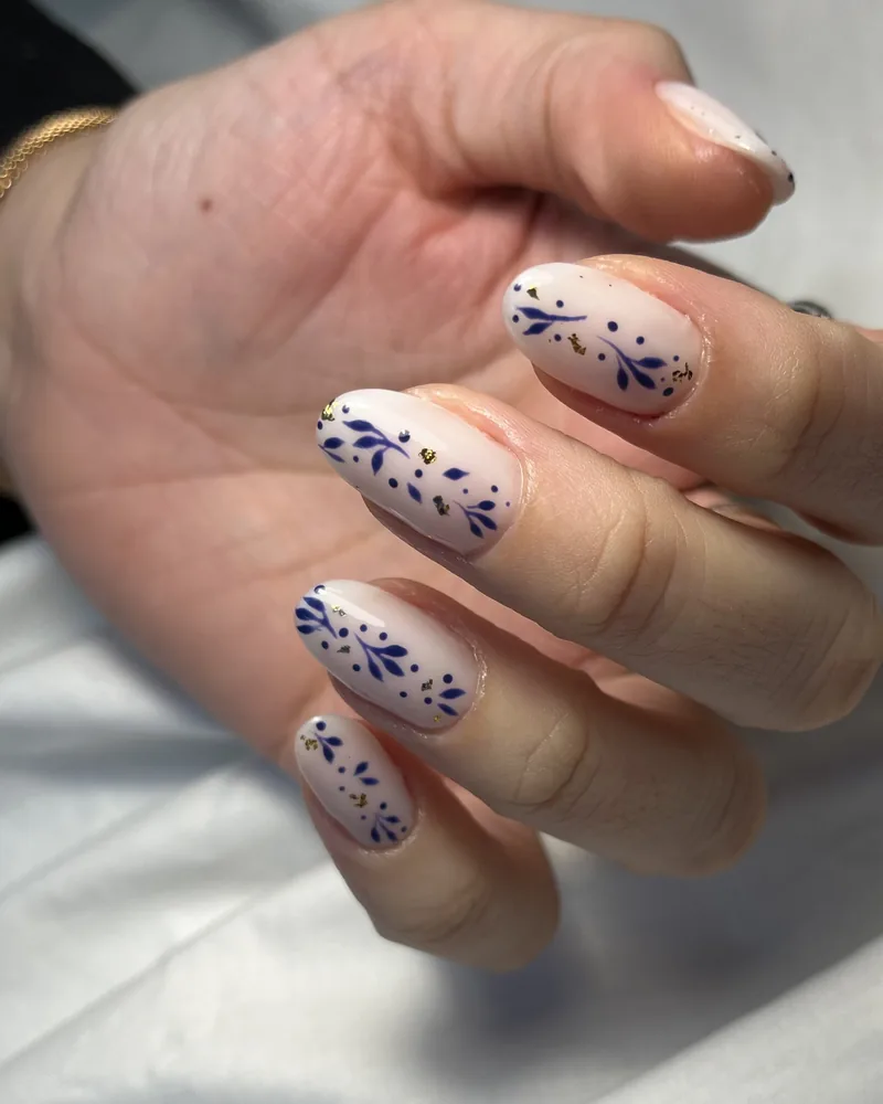 Nail art : motifs bleus peints à la main sur ongles nude en amande